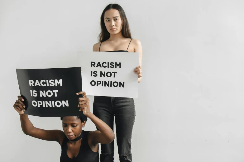 two women holding signs that read racism is not opinion