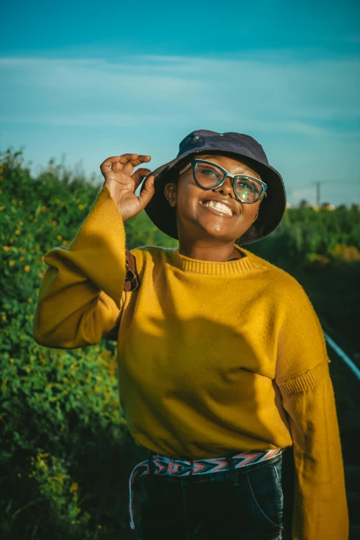 a black woman in yellow sweater, glasses and a hat