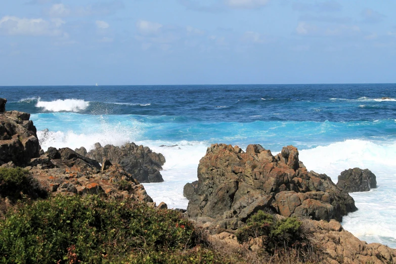 a rocky shore with blue ocean and large rocks