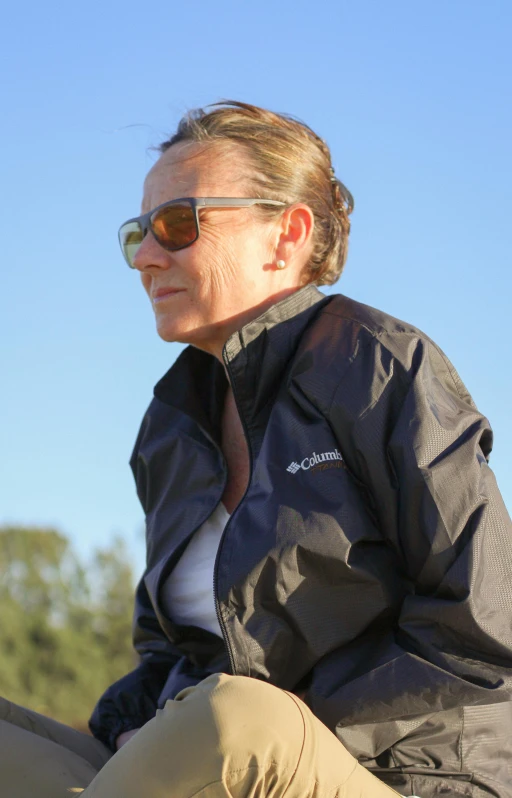 a woman wearing sun glasses while sitting on the ground