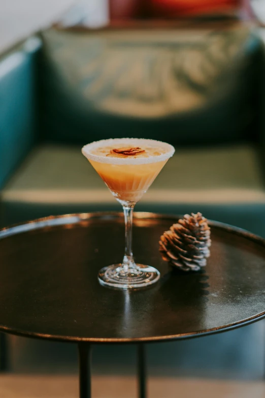 the drink is on a table beside a pine cone