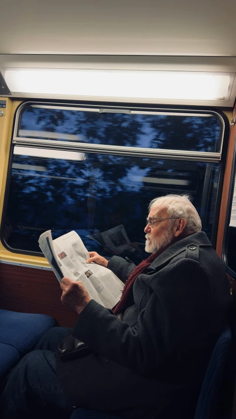 older man reading in passenger car with window open