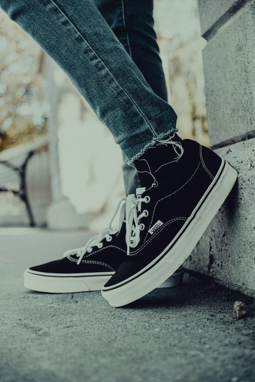 person standing on concrete curb wearing black and white sneakers