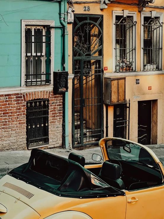 two old yellow cars parked in front of buildings