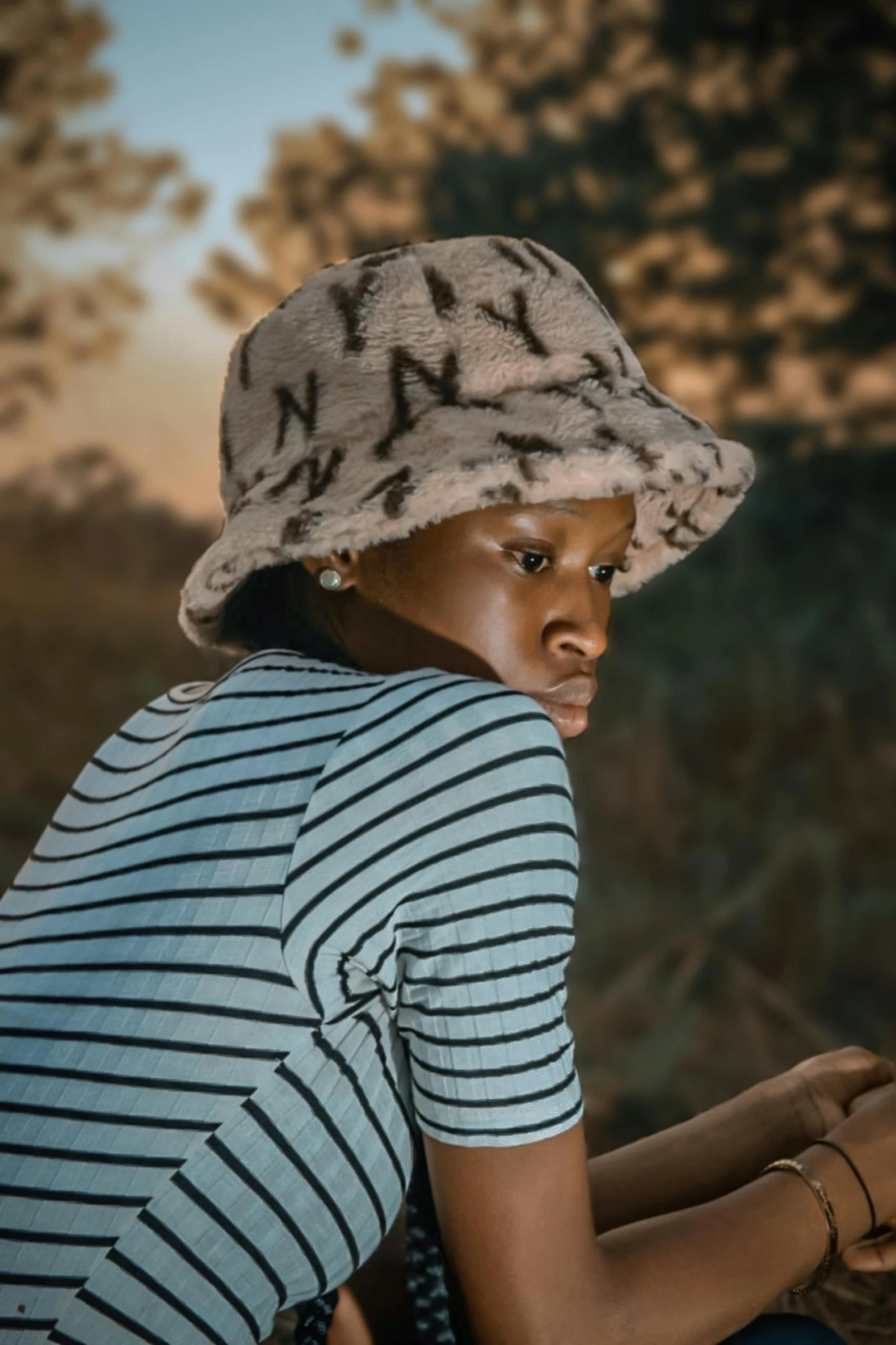 the young woman is wearing a hat and striped t - shirt