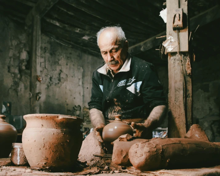 an old man making vases using clay