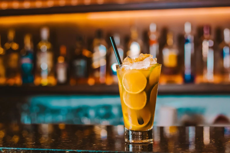 a glass on a bar with a lemon drink in it