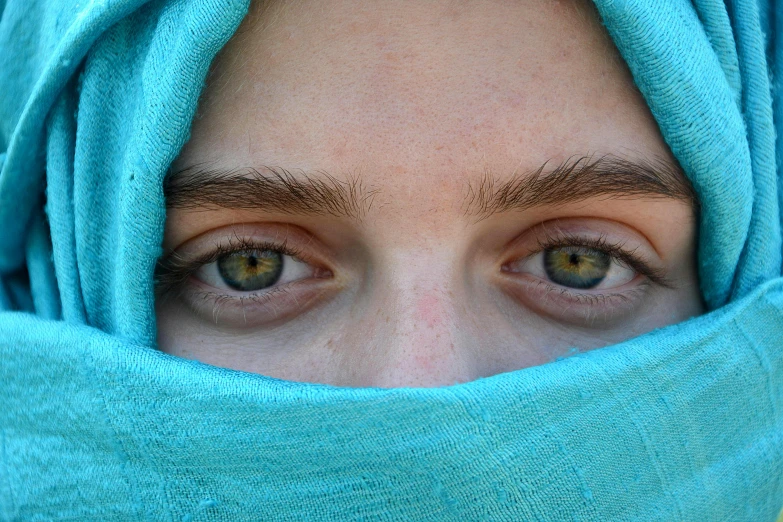 a person with green eyes wearing a blue blanket