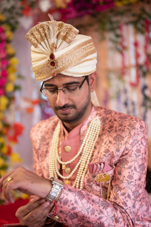 a man in a gold outfit looks down at his watch