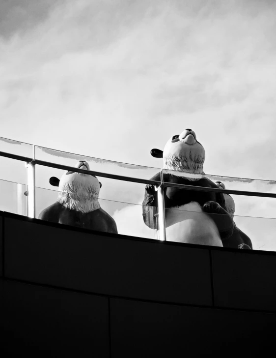 a couple of large snowmen sitting behind a fence