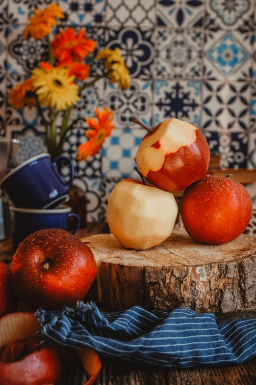 apples stacked on a small wood piece by flowers