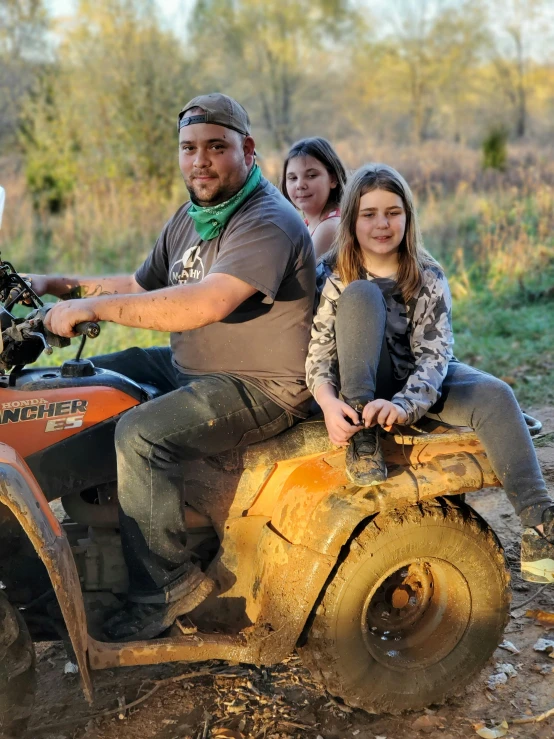 a man and two girls are riding on an atv