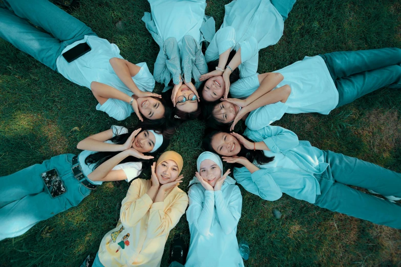 a group of women laying in the grass with heads together