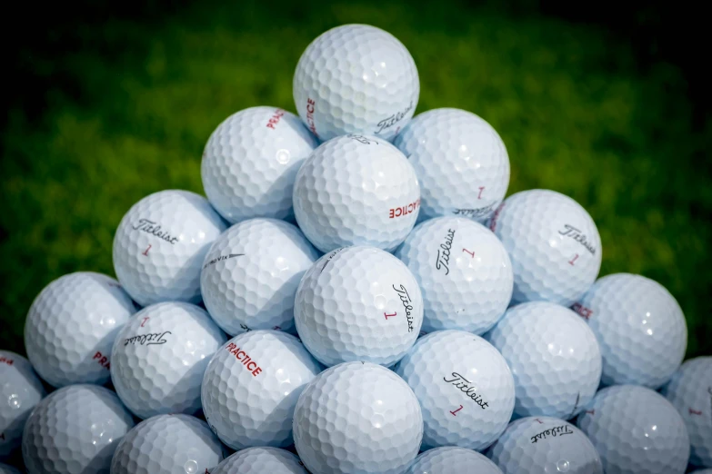 a pile of many white golf balls in the grass
