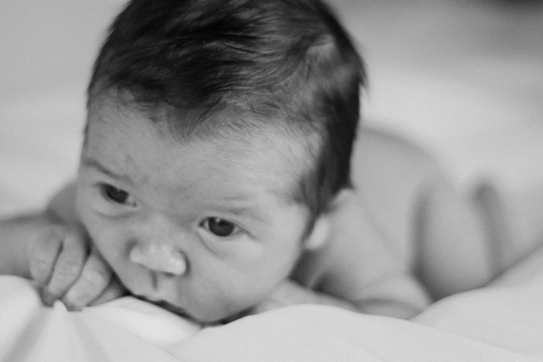 a young baby laying in a bed with a blanket