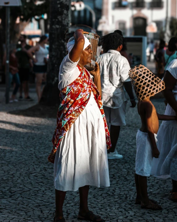 several people in white outfits carrying baskets near a street