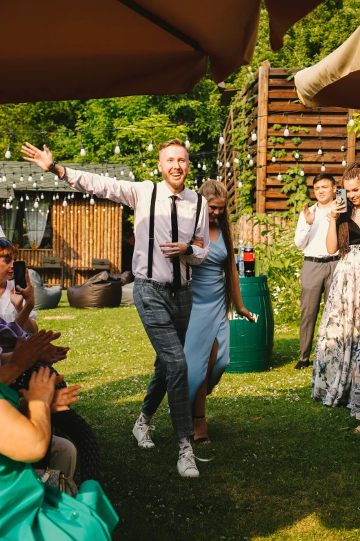 two people walking on grass and being greeted by a crowd of people