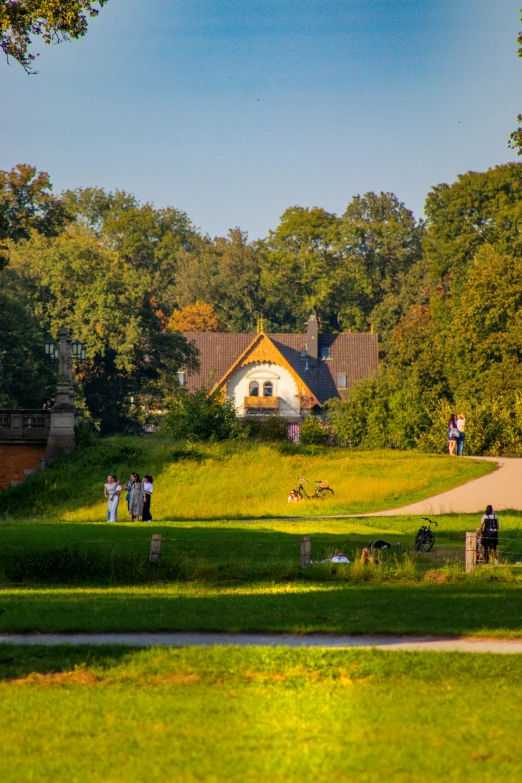 people walk up and down the green grass in front of a white house