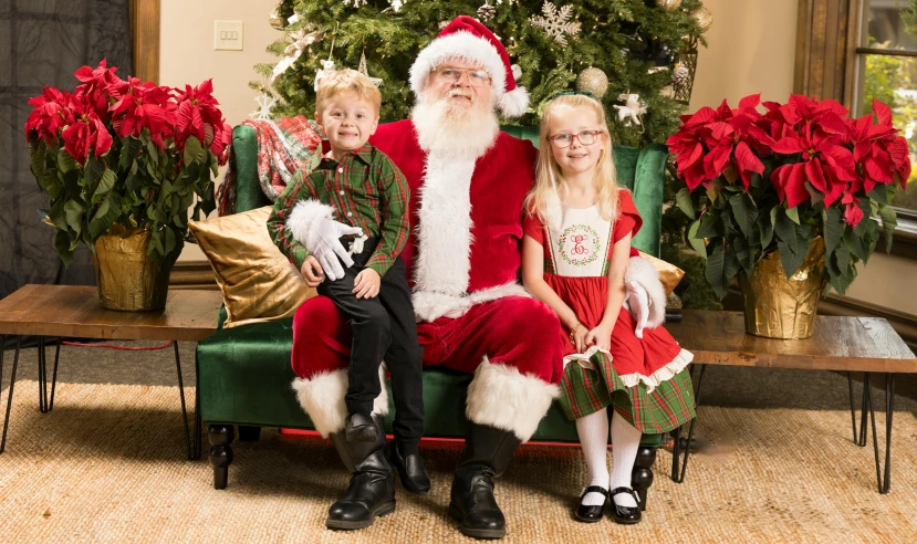 two children sitting on a chair next to santa clause