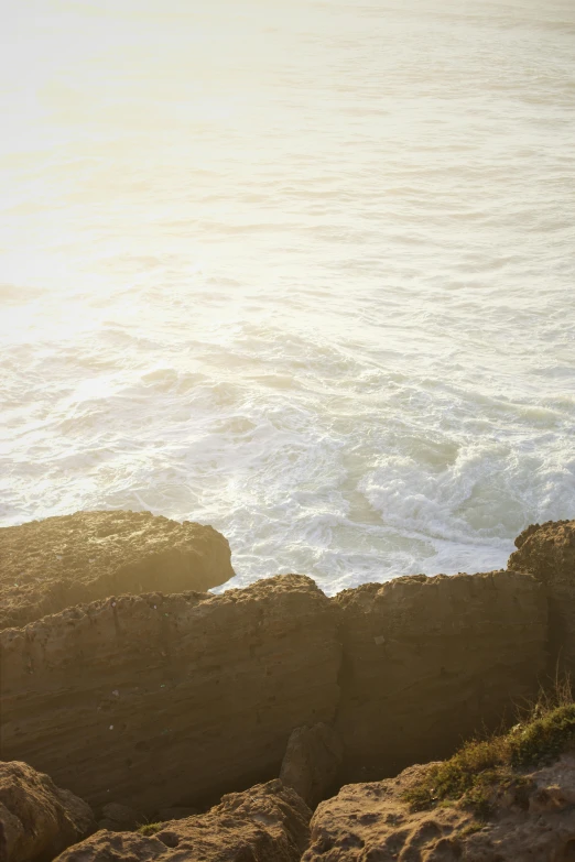 a man standing at the edge of the water looking over rocks