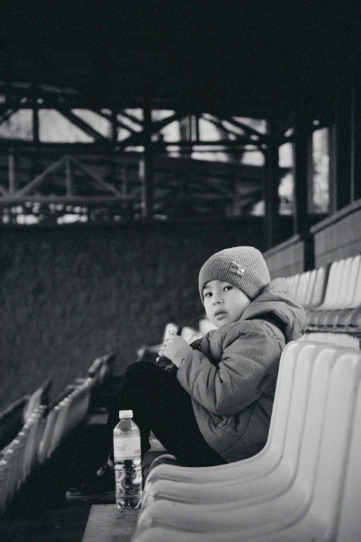 a child sits at the side of a bench in the stands