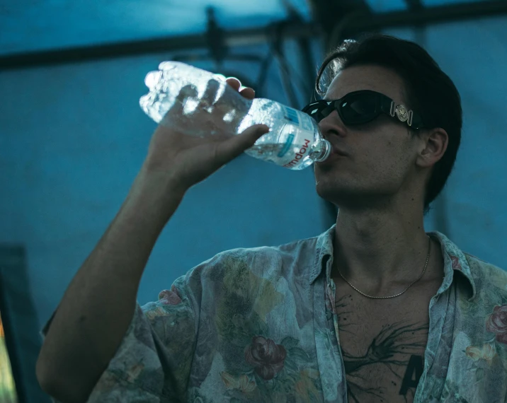 man in sunglasses holding up a bottle with water