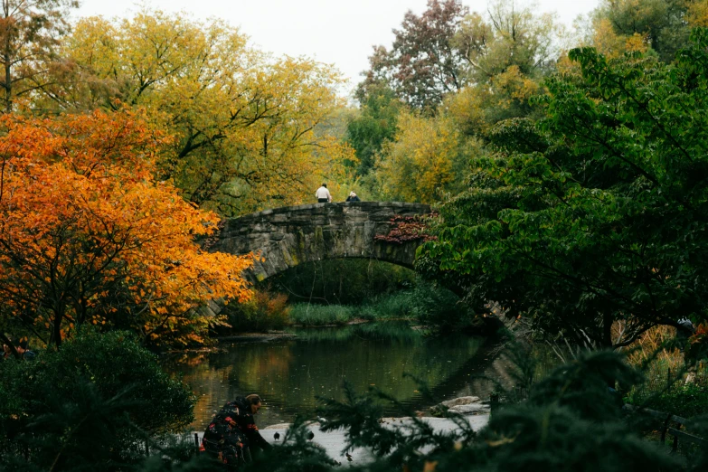 two people in white clothes standing on a stone bridge