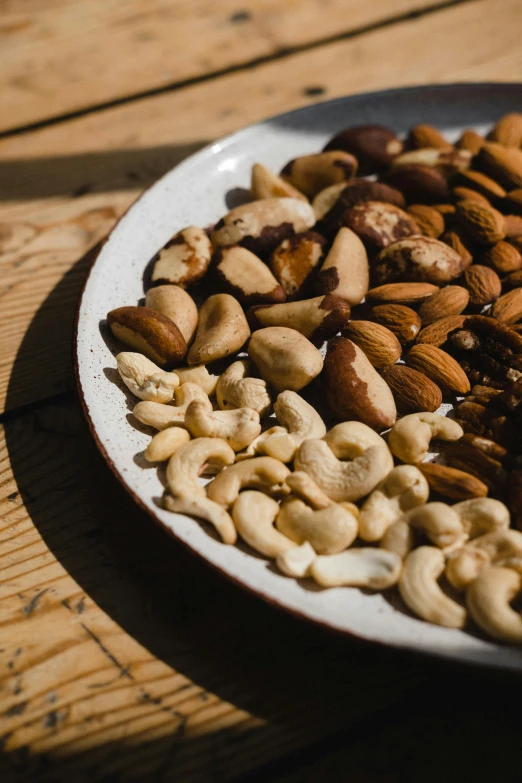 a plate of nuts sitting on a wooden table