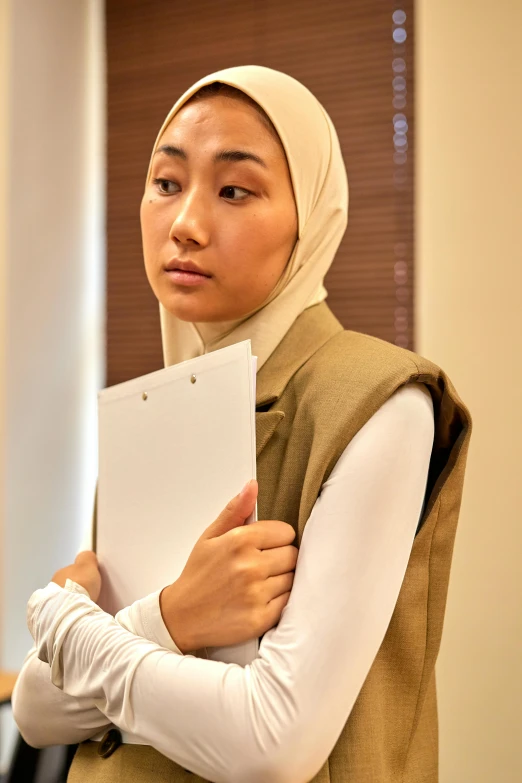 a girl in hijab is holding a book