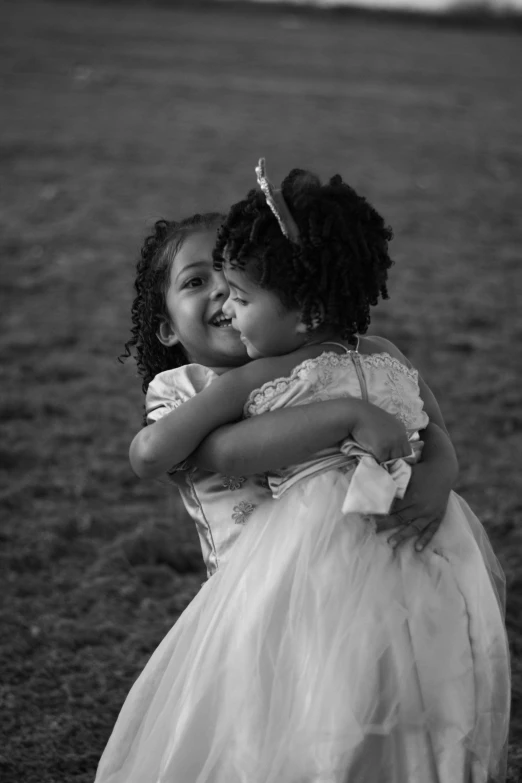 two little girls wearing dresses hugging in an empty field