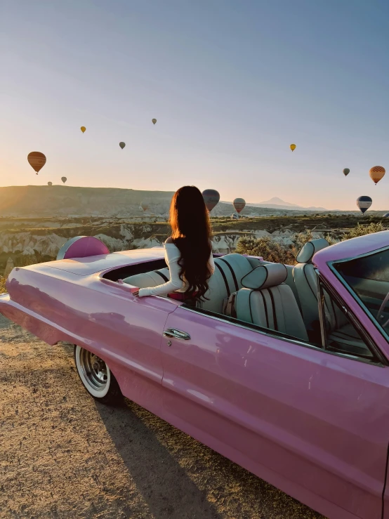 a girl sitting in the back of a car with  air balloons