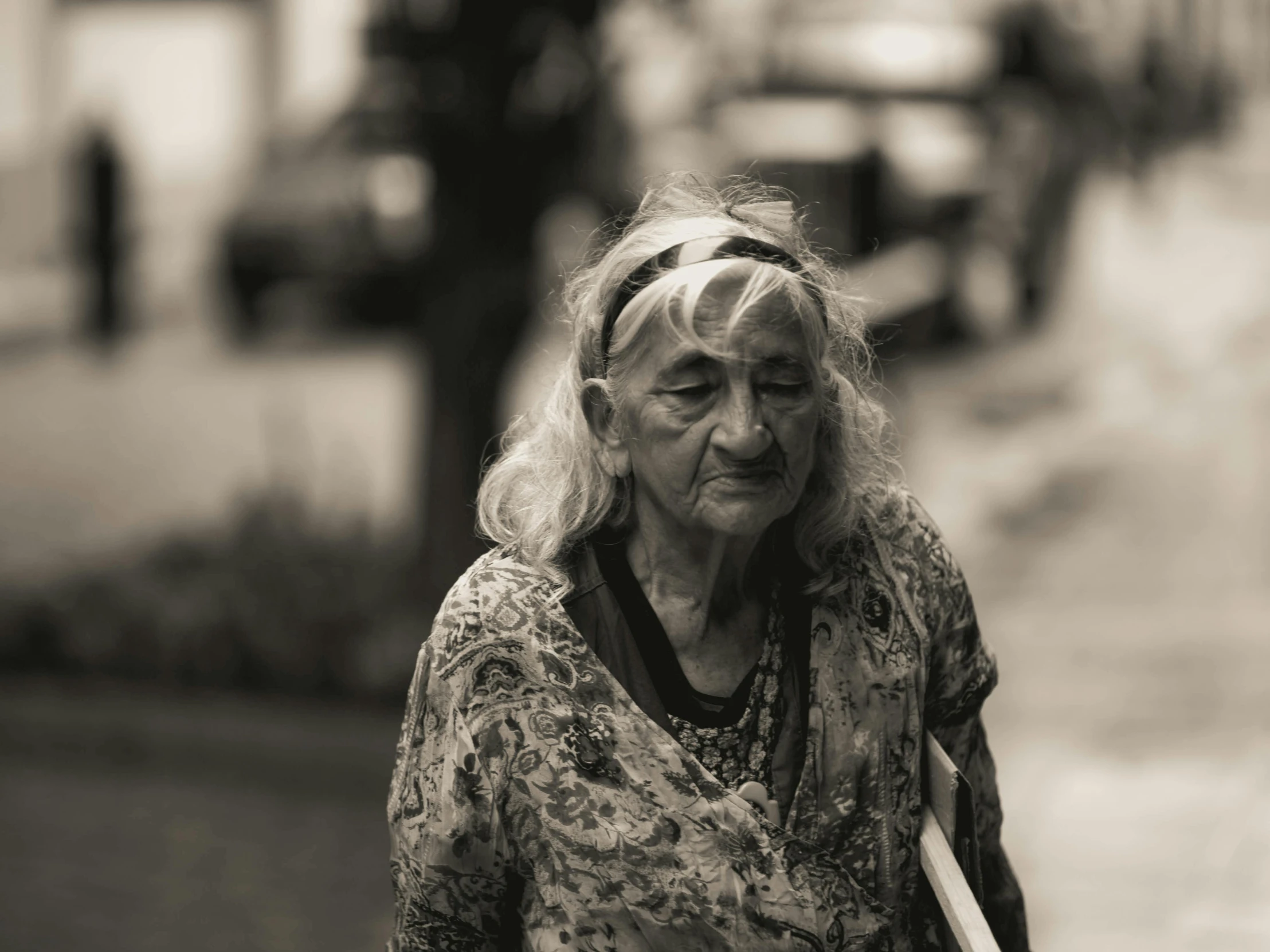 an older woman holding a white umbrella and walking down the street