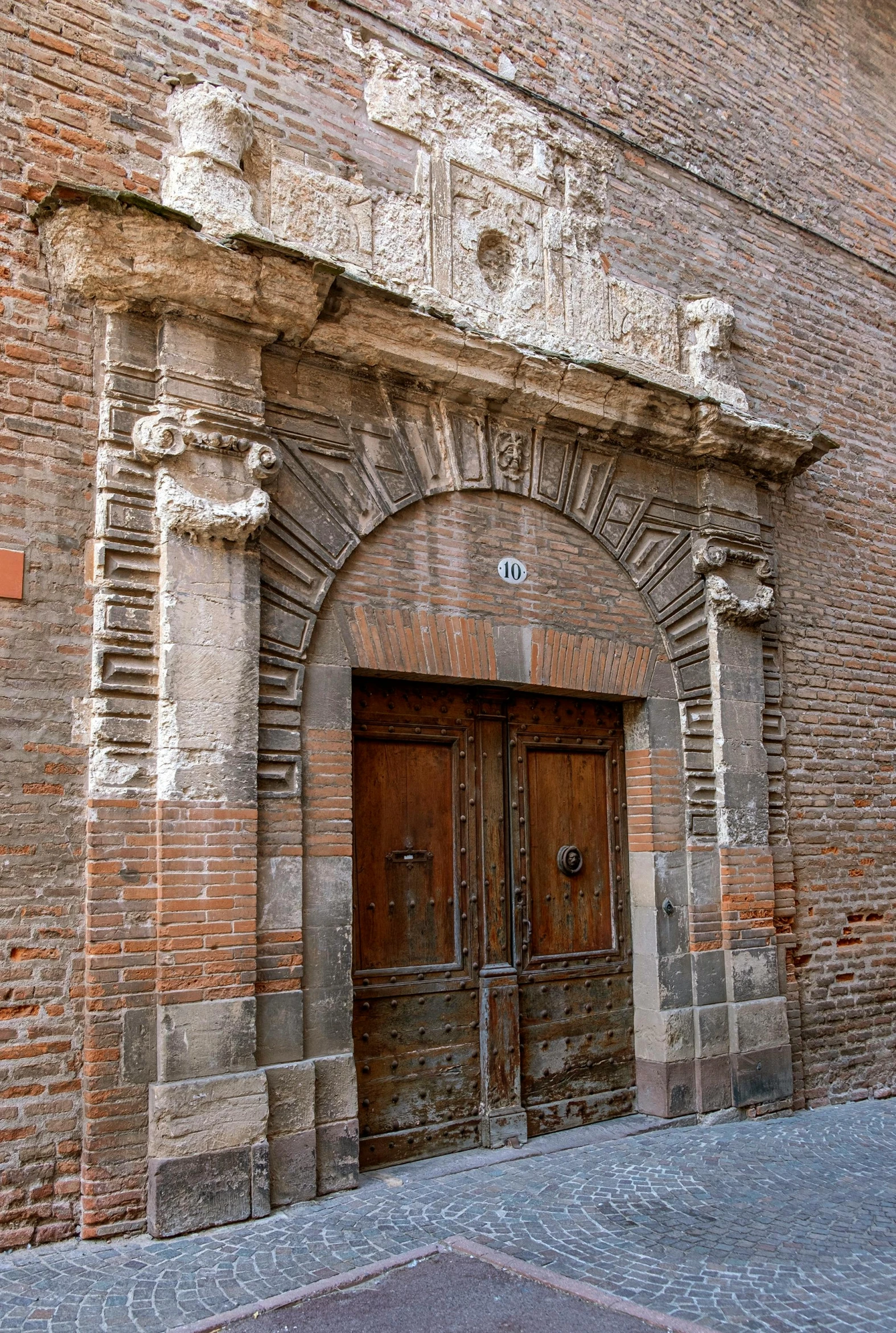 a brown door on a brick building with decorative designs