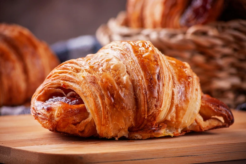 croissants on a  board with some one sliced and the other cut