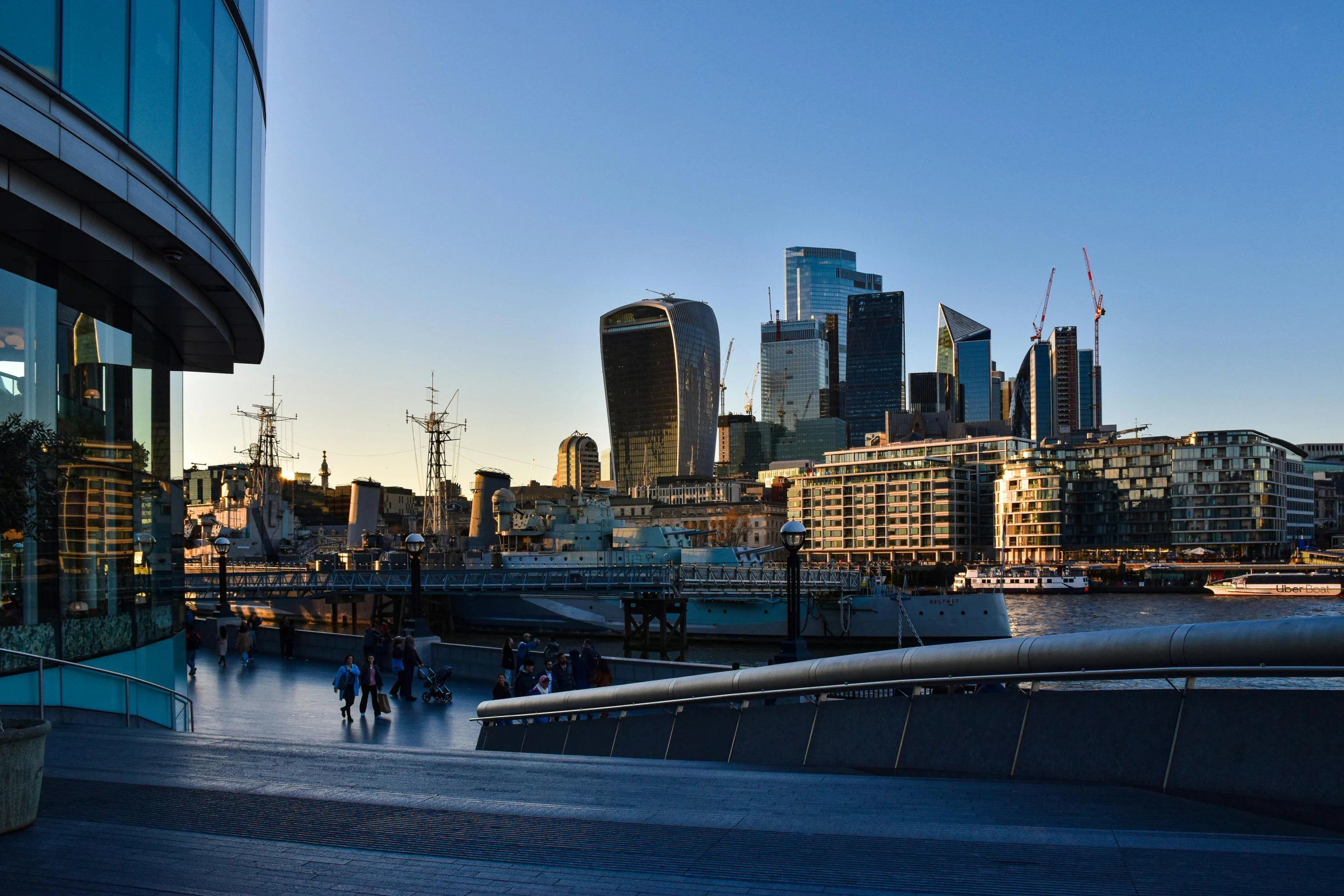 people walk along a pathway in front of a skyline