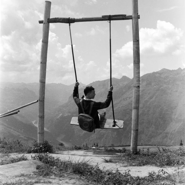 a boy riding on top of a wooden swing set