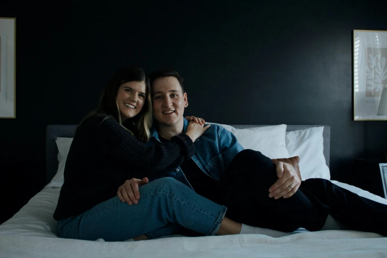 a couple in a black bedroom sitting on a bed