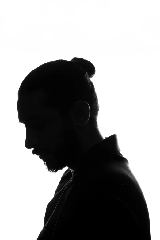 a man in silhouette with a ponytail standing with a phone