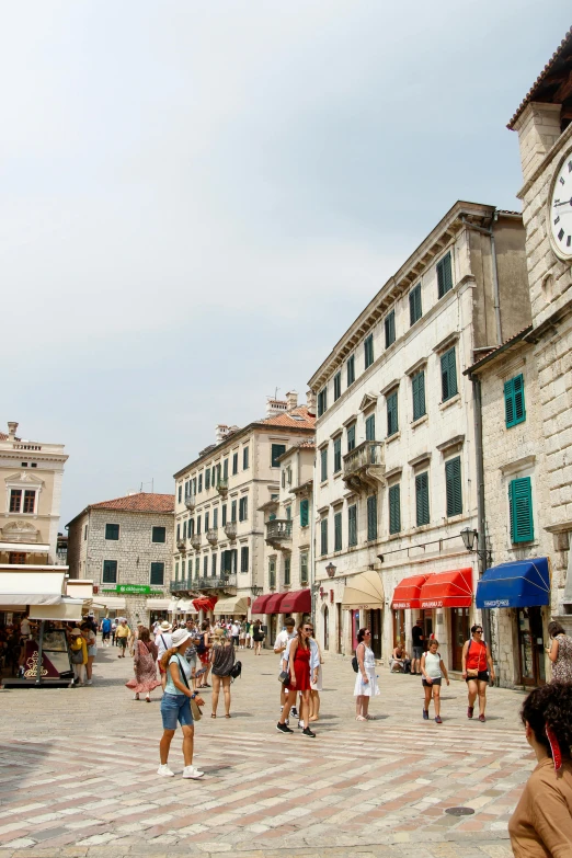 people are in a city square with the clock above