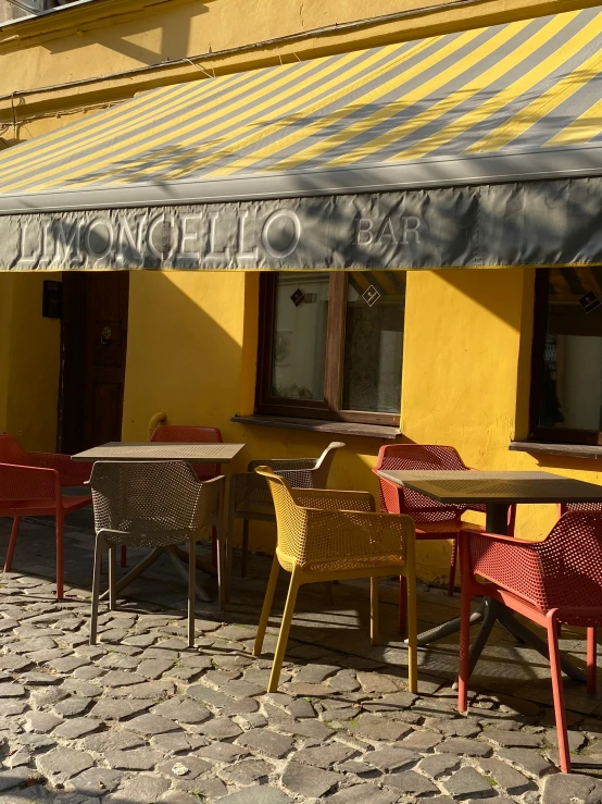 tables with yellow and red chairs near an awning