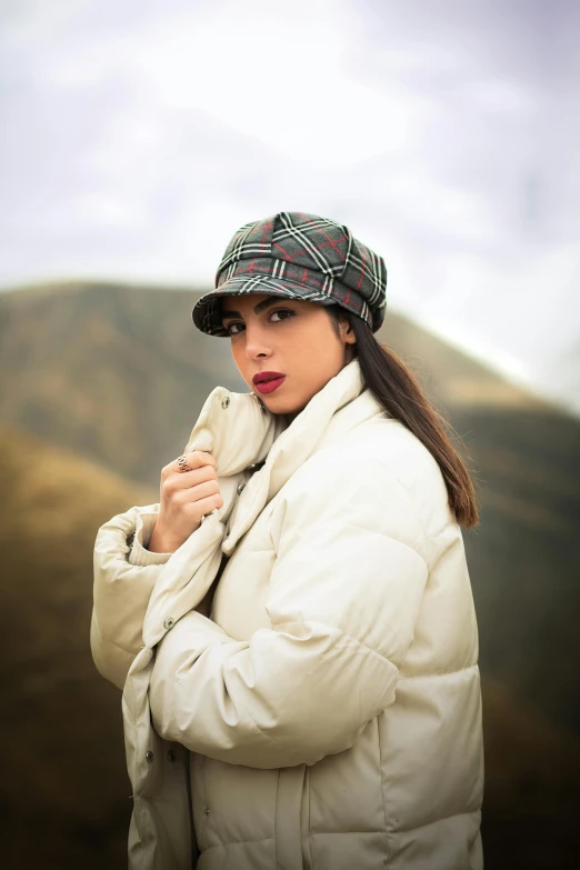 a woman standing with her hat up while wearing a jacket