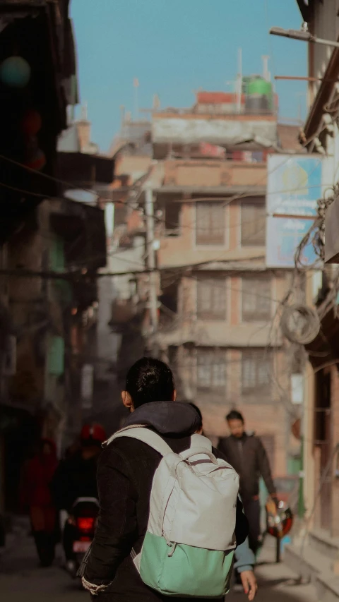 man walking through a slum city area with a backpack