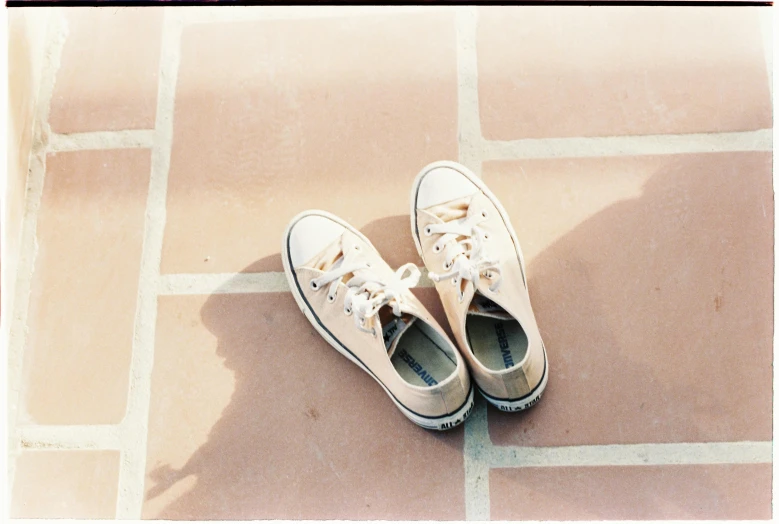 two tennis shoes in front of a tiled floor