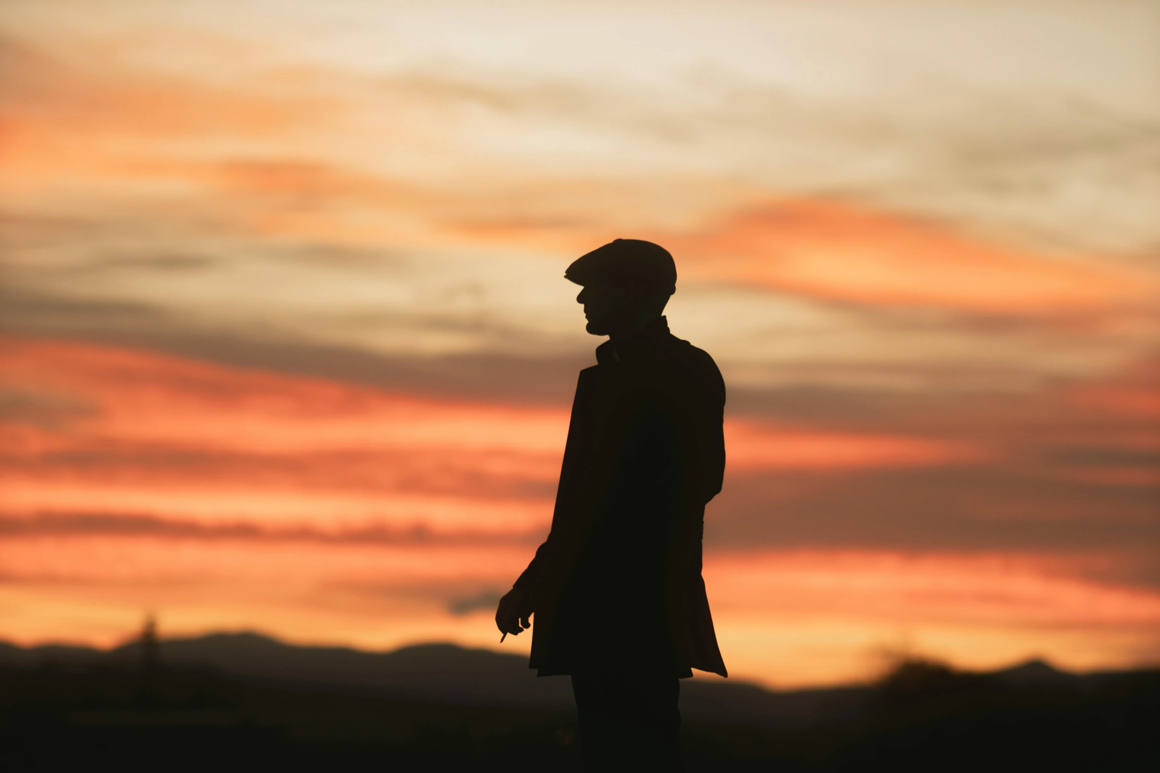 a silhouetted man standing in front of a sunset