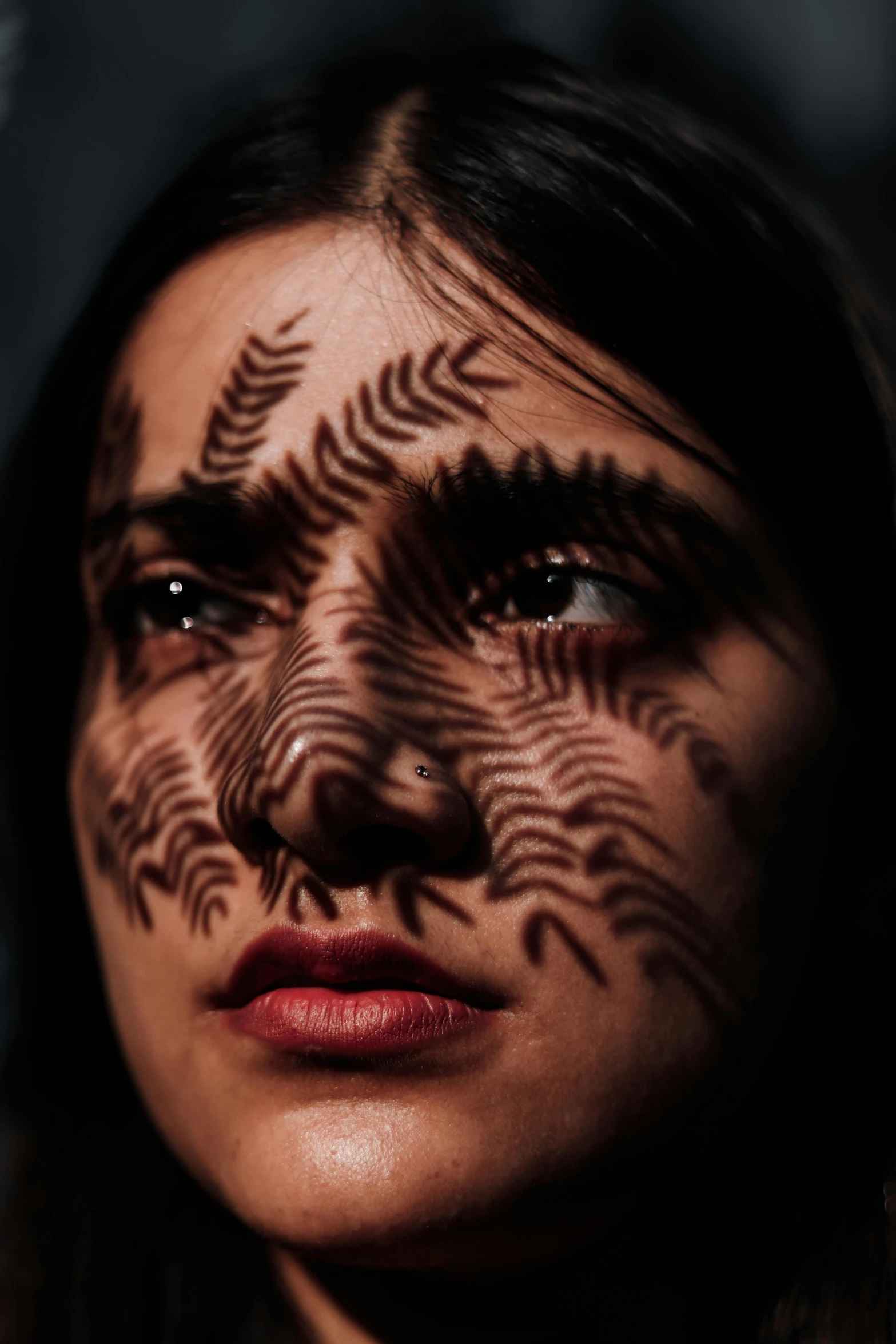 a woman with the sun coming through the leaves covering her face