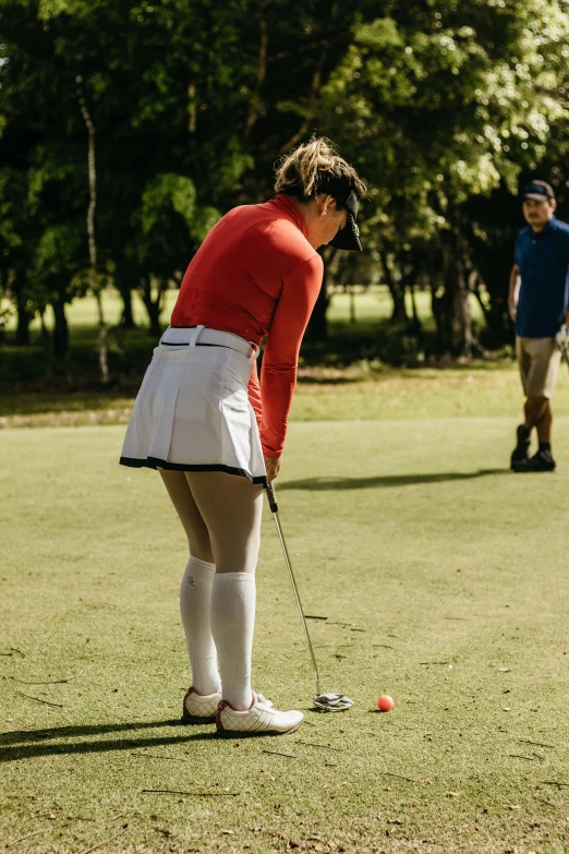 a person in short shorts holding a club near an orange ball