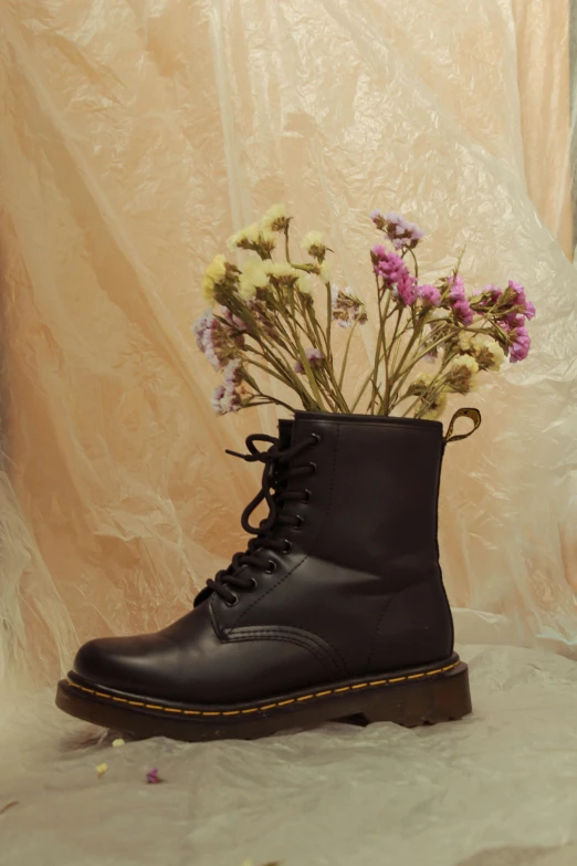 a black pair of boots is holding purple flowers
