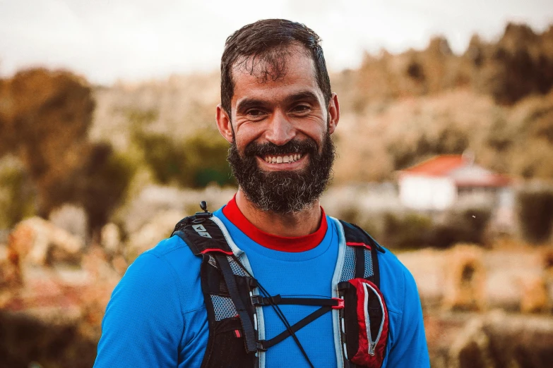 a man with a beard wearing a camera strapped on to his back