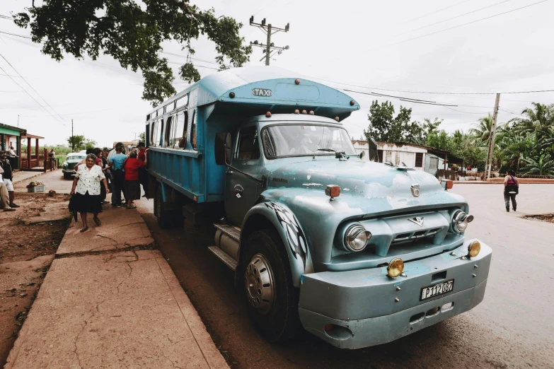 old, very old, light blue school bus on the side of a road