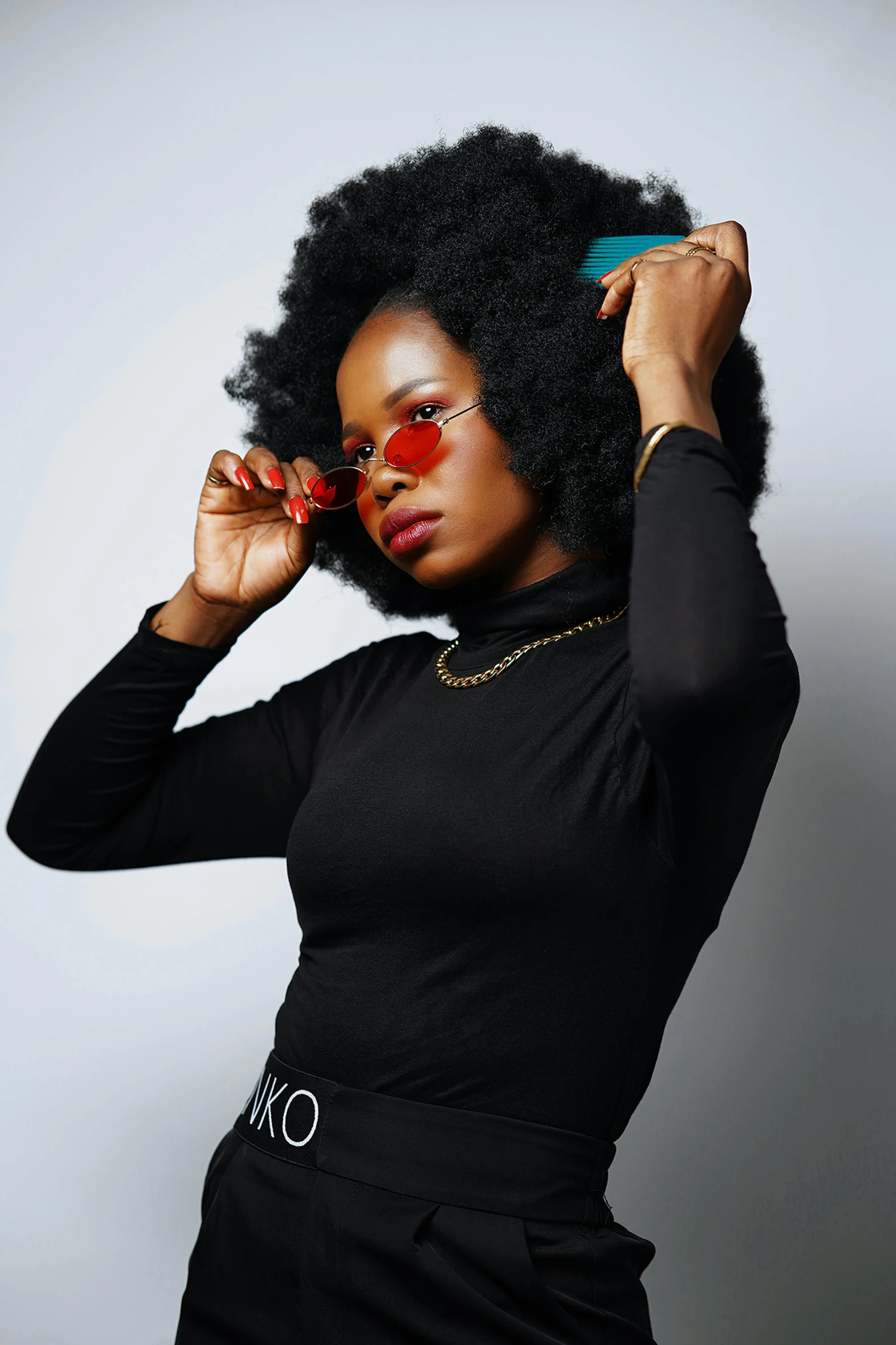 a woman with glasses and big afro holds up a hairbrush